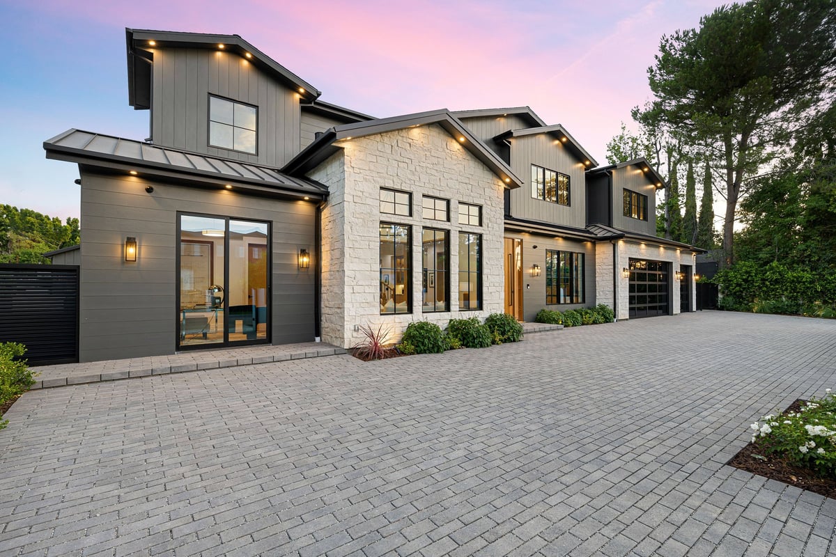 Modern luxury home exterior with large windows and stone facade at sunset